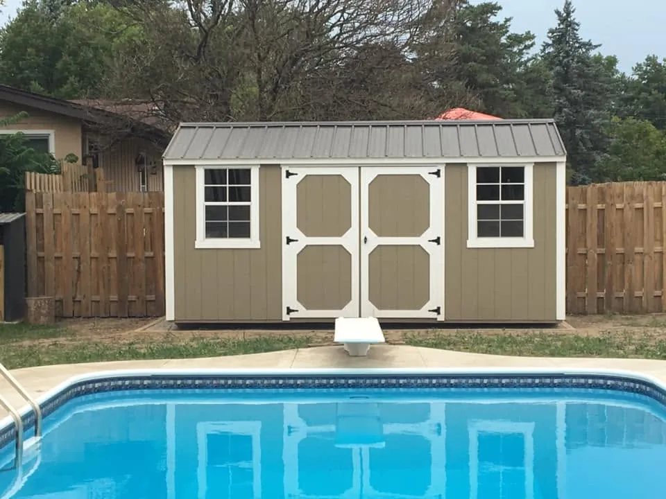Olive shed with white X-brace doors beside swimming pool