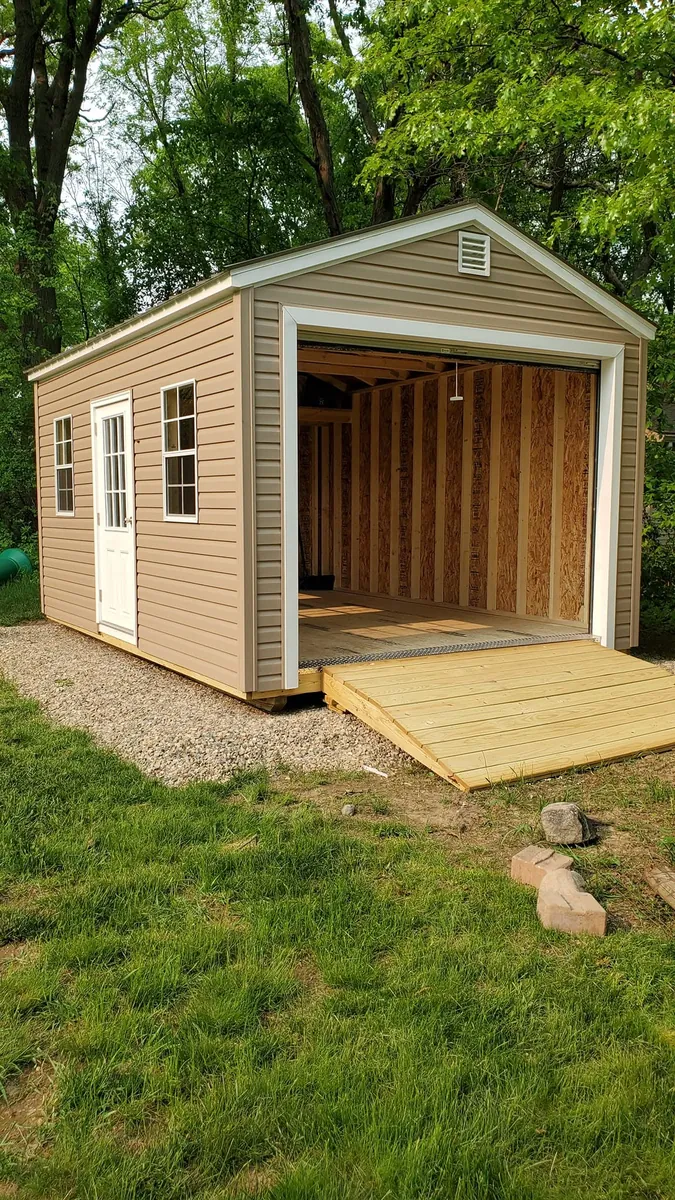 Studio-style tan shed with wide opening and wooden ramp deck