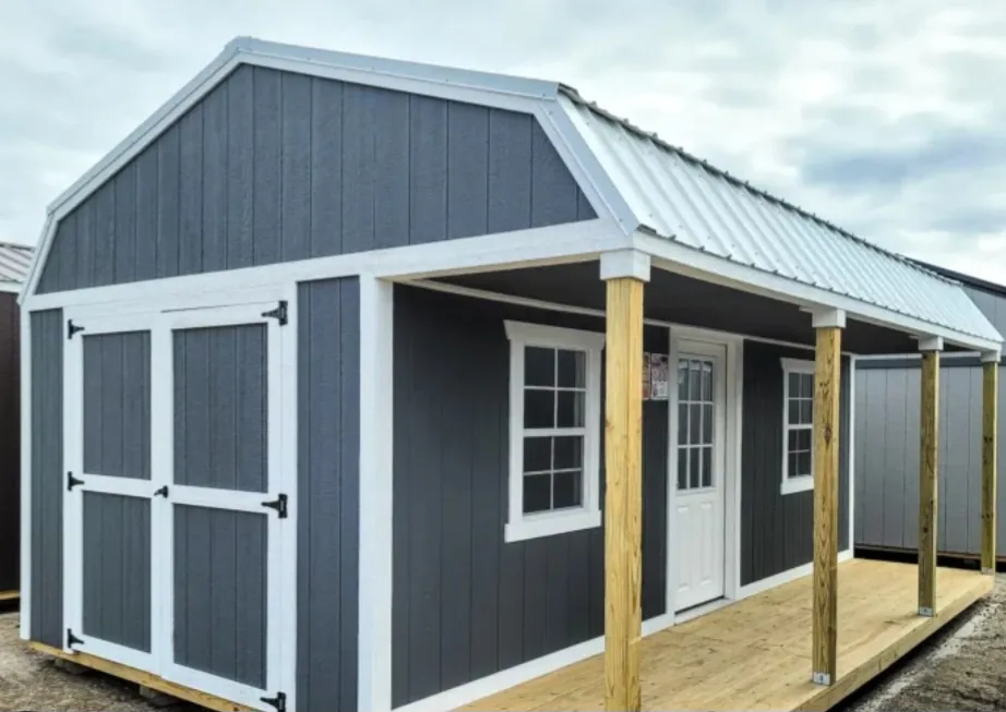 Blue-gray lofted barn cabin with white trim, metal roof, and covered side porch with wood posts.